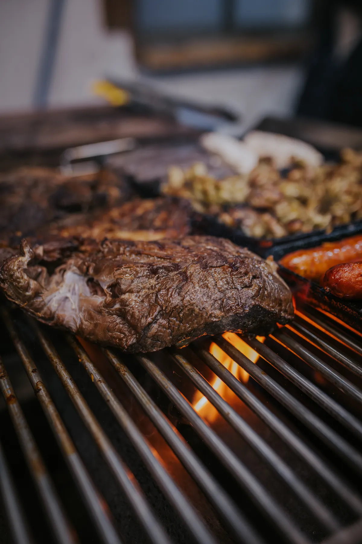 Corte de carne dorándose sobre la parrilla encendida con llamas