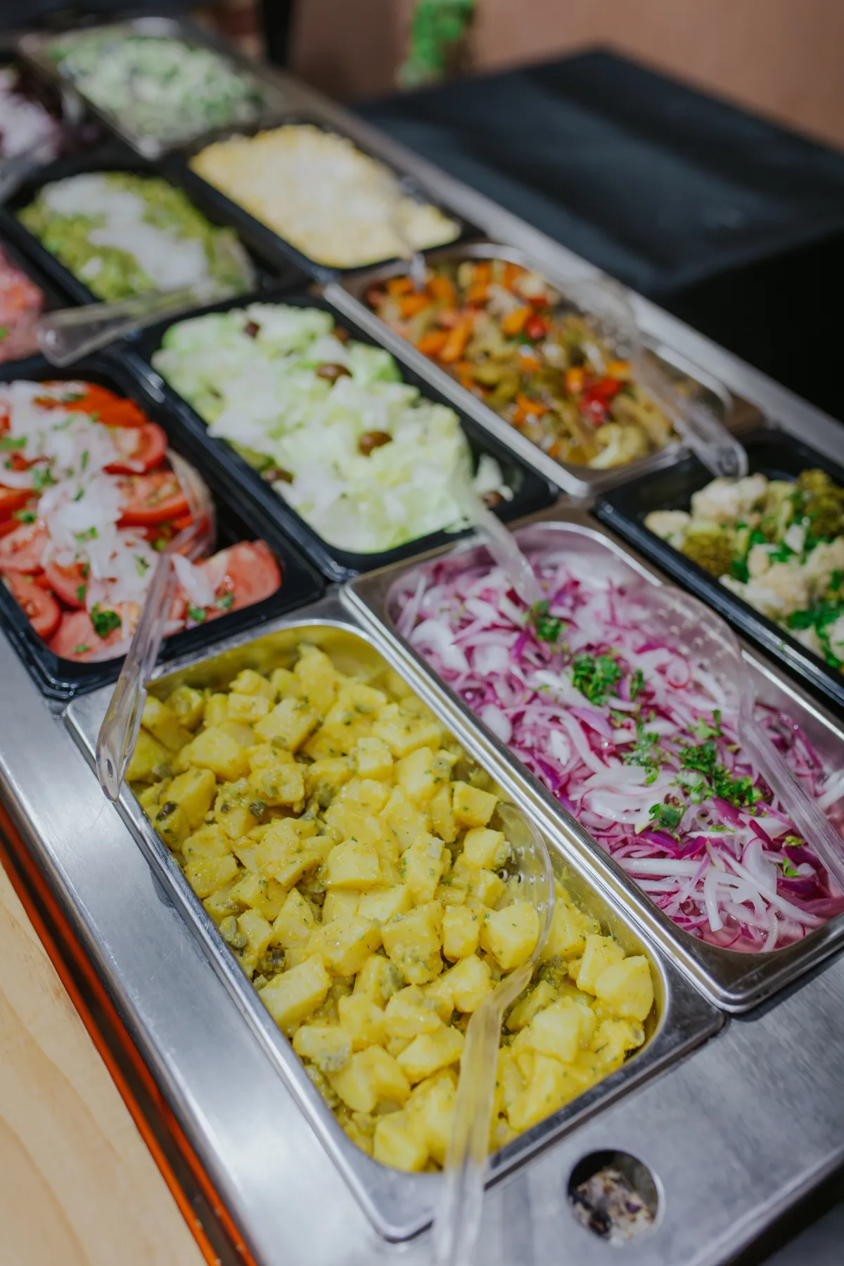 Barra de ensaladas frescas con tomate, papas y verduras variadas