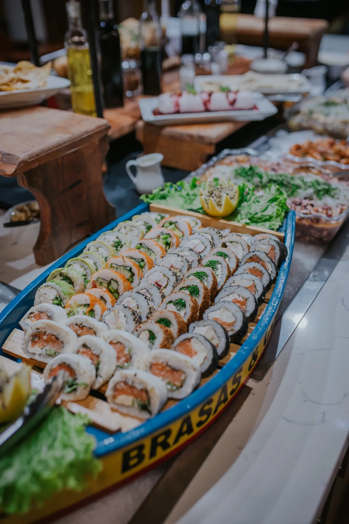 Barca de madera repleta de rolls de sushi variados en el buffet
