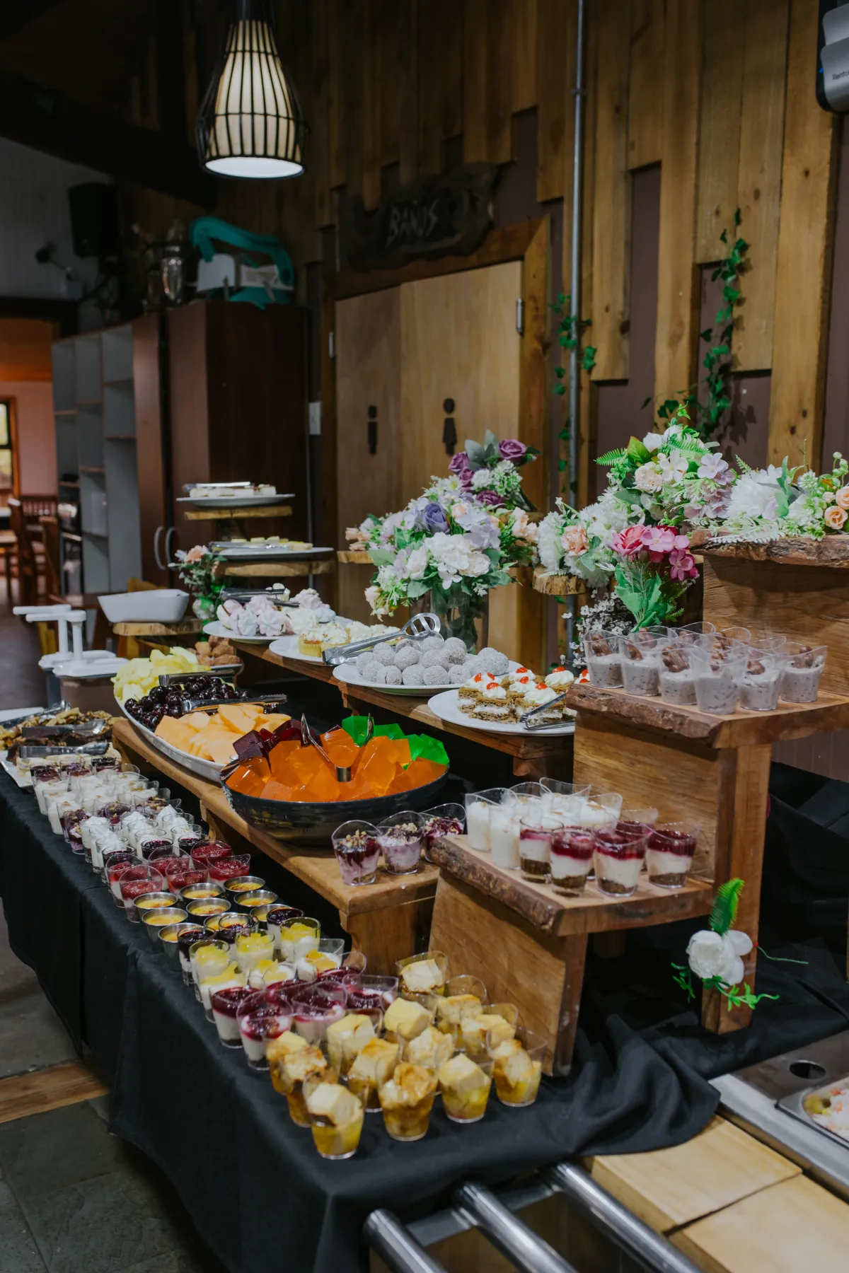 Mesa de postres con mini tortas, mousses y vasitos decorada con flores
