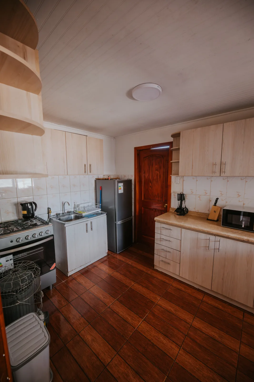 Cocina de cabaña con muebles claros, refrigerador, cocina a gas y piso de madera