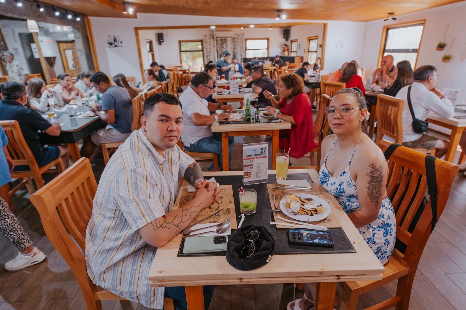 Pareja sonriente en su mesa con bebidas frescas en el salón