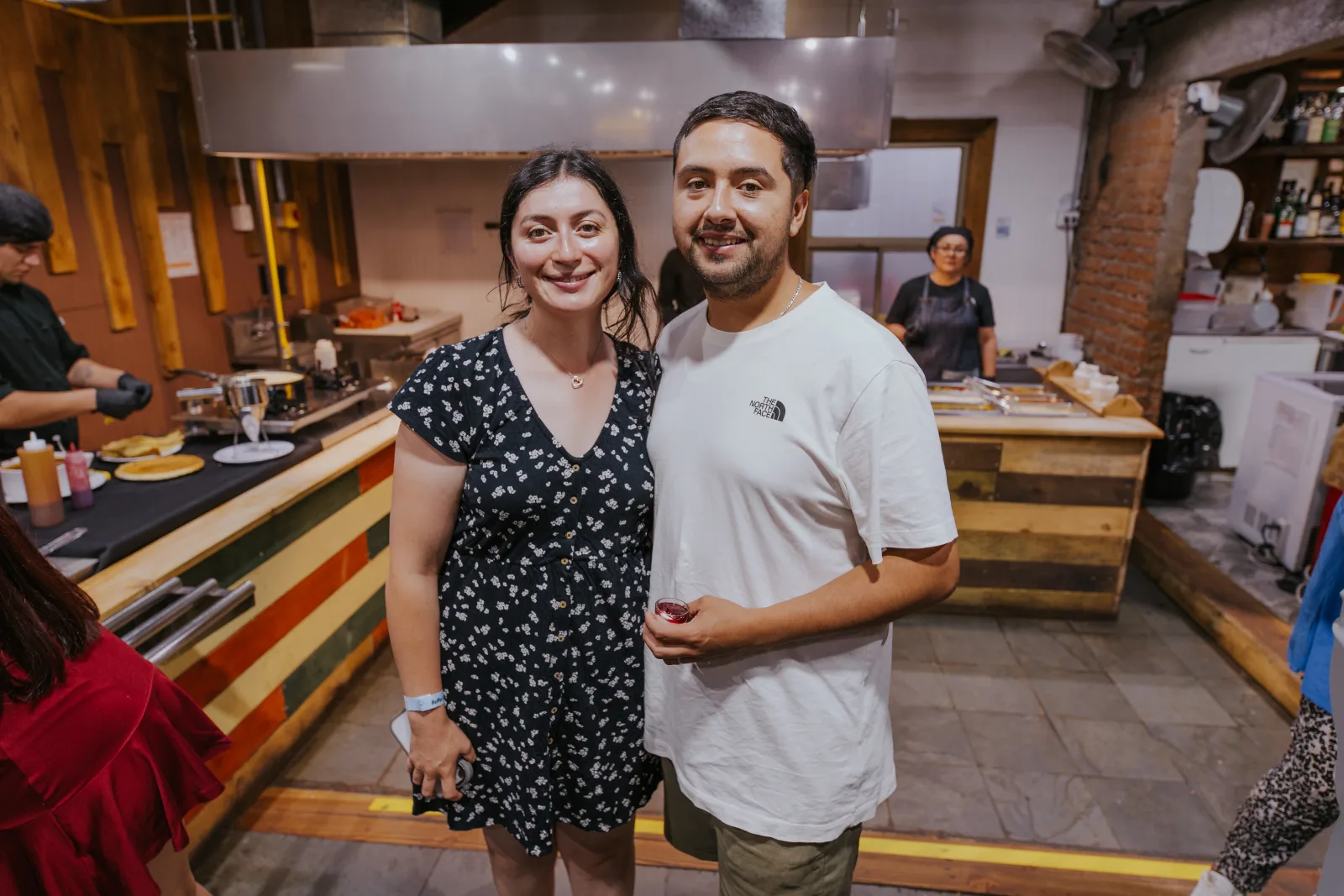 Pareja sonriente frente a la zona de cocina y estaciones del buffet