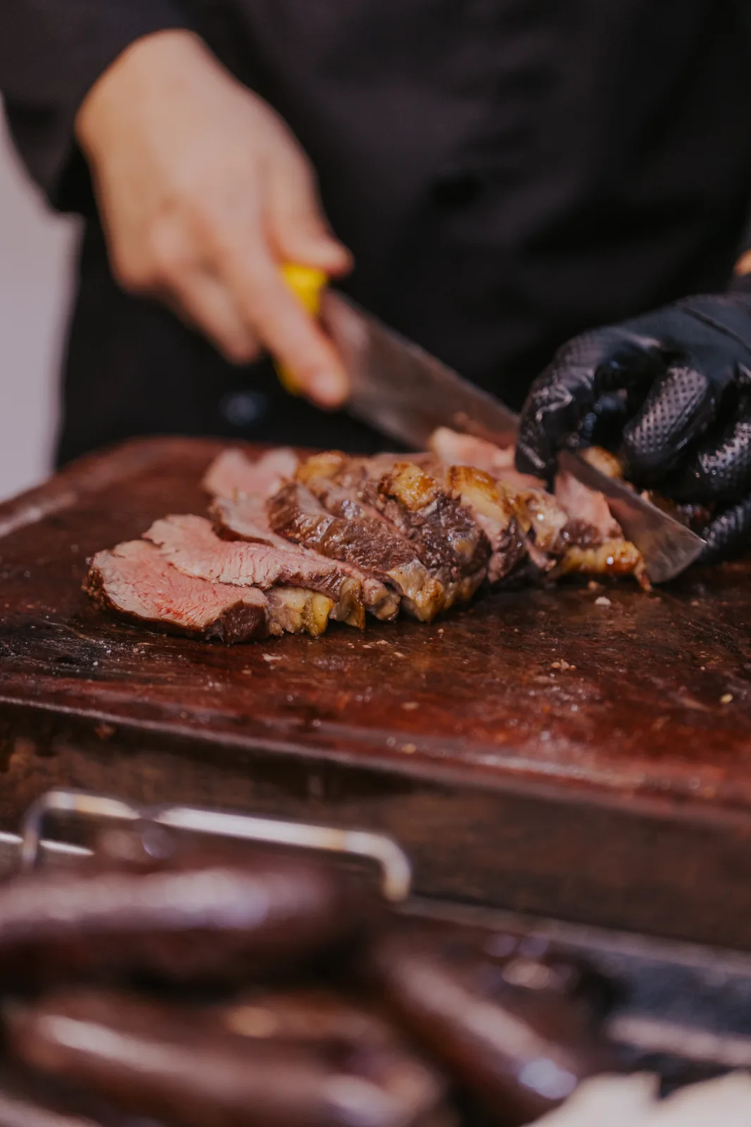 Chef cortando jugosos cortes de carne a la parrilla sobre tabla de madera