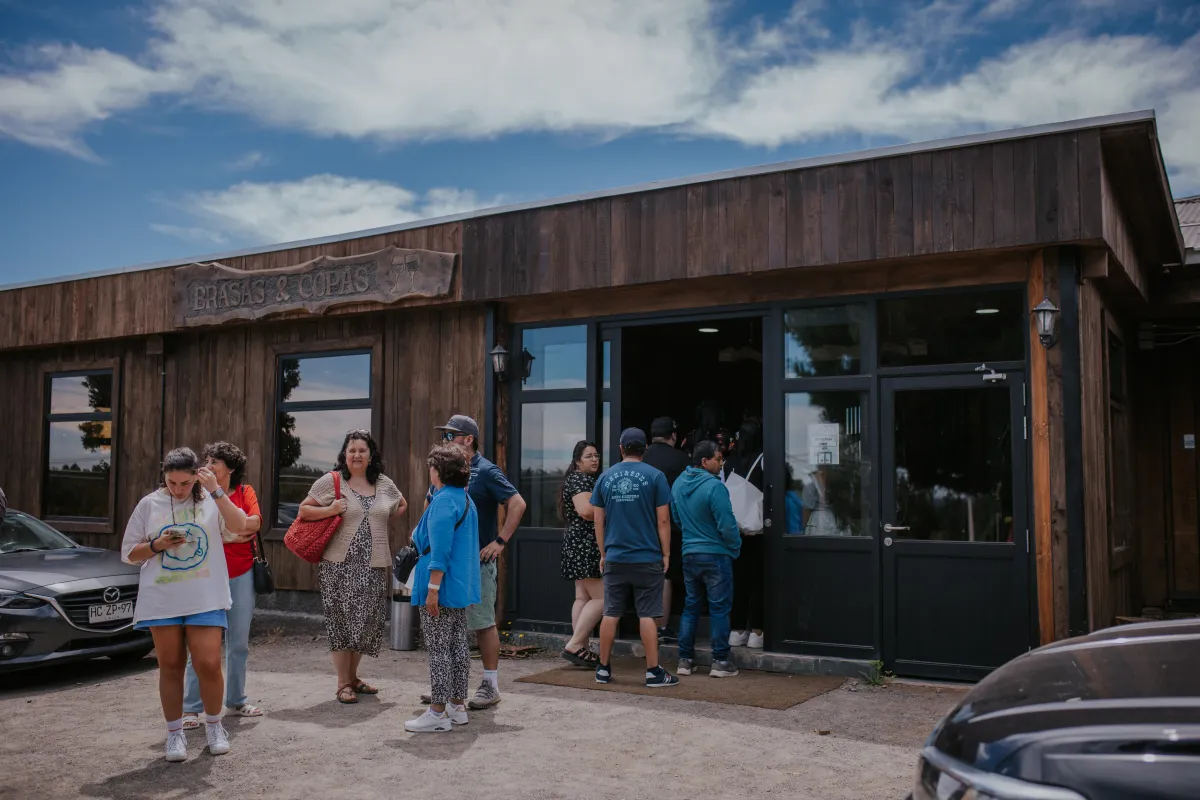 Fachada de madera del restaurante Brasas y Copas con clientes en la entrada